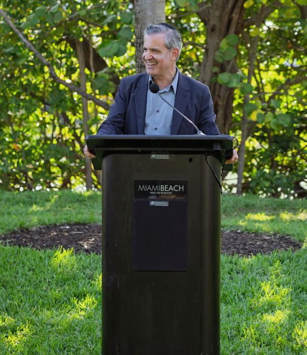 Man speaking at a podium with a Miami Beach logo